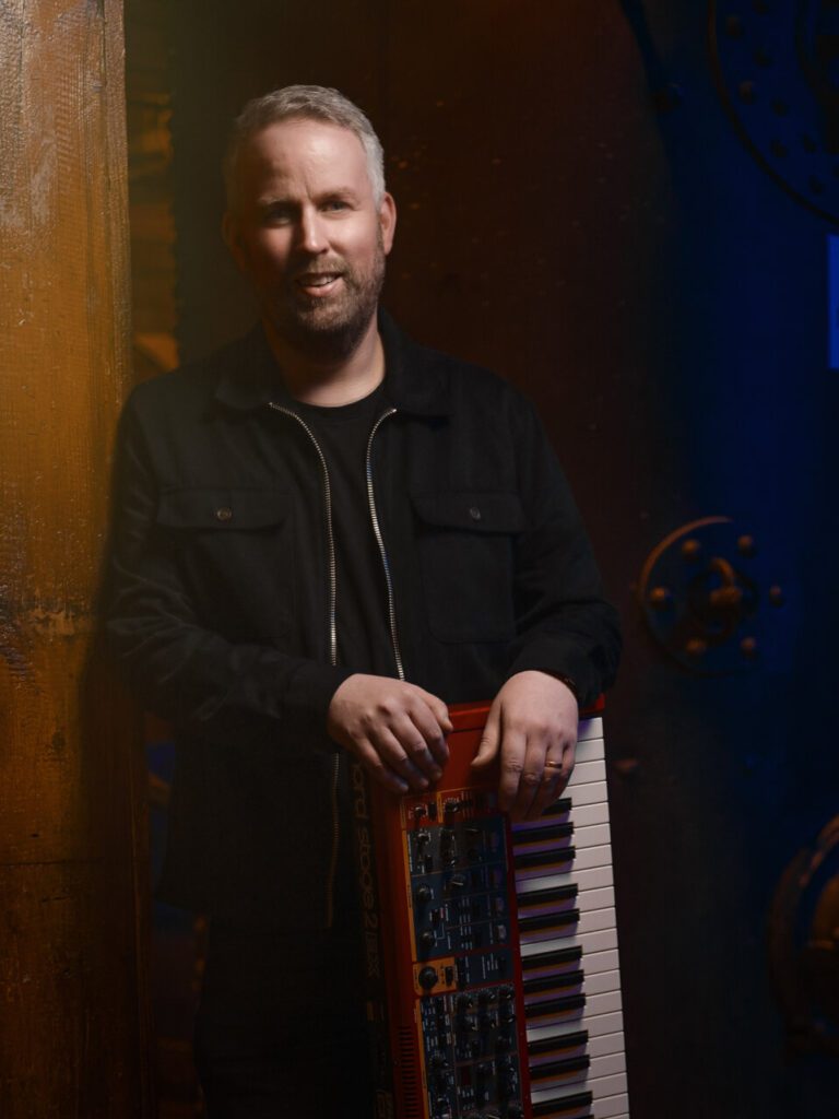 Dave Mongan is smiling and holding a keyboard.